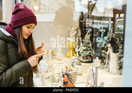 Une belle jeune femme ou une jeune fille regarde la vitrine et choisit un cadeau de Noël. Banque D'Images