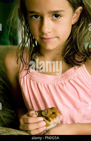 Un portrait d'une jeune fille (5-8 ans) maintenant son animal de hamster. Banque D'Images