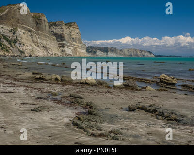 Sur une belle journée ensoleillée, marée basse expose des crêtes pierreuses dessous des falaises le long de Cape Kidnappers sur Hawkes Bay en Nouvelle Zélande. Banque D'Images