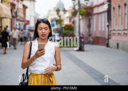Asian girl en utilisant un téléphone intelligent dans la rue Banque D'Images