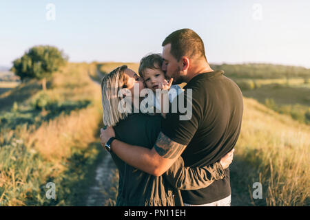 Heureux parents kissing adorable petit fils à l'extérieur Banque D'Images