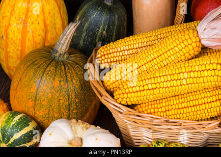 Motif de l'action de l'automne avec un panier plein d'épis de maïs et les différentes citrouilles coloré sur un fond de bois rustique Banque D'Images