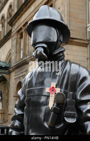 Le citoyen bronze statue pompier hommage orné d'une croix en bois et de pavot dévouement à la 911 morts Glasgow, Écosse, Royaume-Uni. Banque D'Images