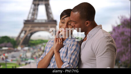 Ethnique joyeux couple nouvellement engagée, debout près de la Tour Eiffel à Paris, France Banque D'Images