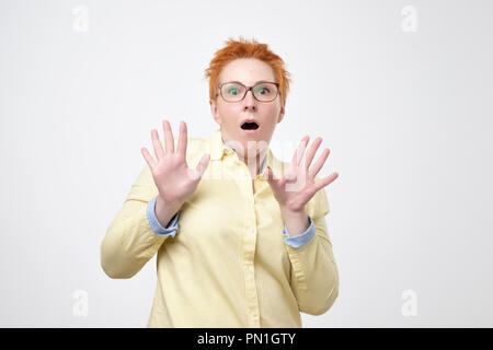 Oh pas de concept. Portrait de femme européenne attrayante avec des lunettes habillé en chemise jaune looking at camera, en gardant la bouche grande ouverte se sentir choqué Banque D'Images