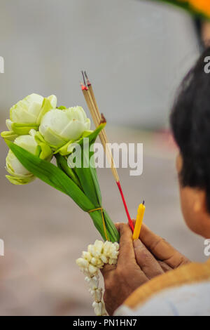 Close up personnes mains tenant d'encens, bougie, fleur de lotus et garland tout en mérite pour la cérémonie du culte. Banque D'Images