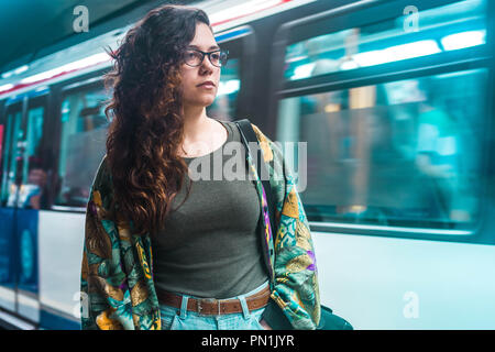 Jeune femme brune avec de longs cheveux bouclés à l'aide de l'attente de la station de métro Métro à Madrid la mode hippie chic mignon Banque D'Images