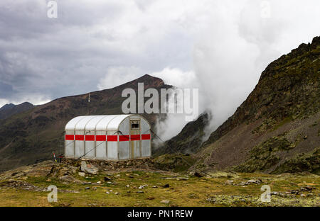 Un petit refuge de montagne en acier est situé en face de la montagne d'être rempli par le brouillard et la brume avant une tempête. Banque D'Images