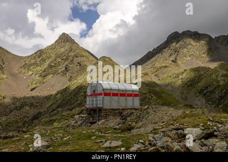 Un petit refuge de montagne en acier se trouve en face de deux sommets. Banque D'Images