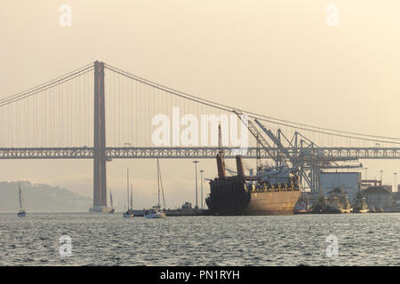 Un cargo est amarré dans le Tage à côté du pont 25 de Abril. Banque D'Images