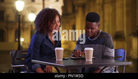 African American man and woman s'asseoir à l'extérieur à l'aide d'appareils à écran tactile Banque D'Images