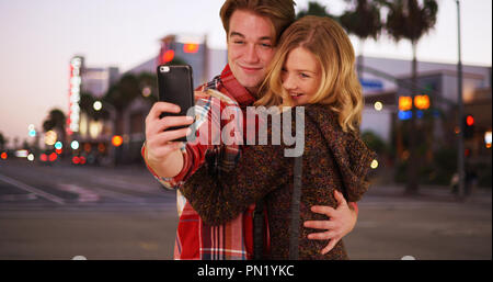 Couple millénaire ou amis qui pose pour les selfies downtown de soir Banque D'Images