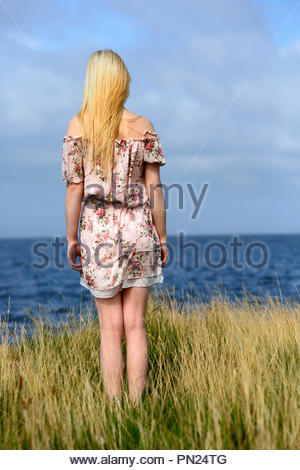 Femme blonde en tenue d'été surplombant la mer Banque D'Images