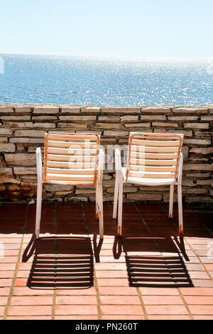 Chaises blanches sur un balcon. Littoral méditerranéen traditionnel et le temps de repos sur la terrasse et chaises anciennes blanc mer bleu incroyable. Chaises vides sont à la Banque D'Images