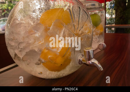 Close up de parti de pique-nique avec table en verre parc grand pichet et bouteilles en verre rempli de glace limonade rose froid et de citrons frais, rose tourbillonné st Banque D'Images