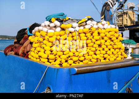 Flotteurs jaune sur la pile, pour les filets de pêche sur le bateau bleu dans le soleil de l'été. Flotteurs de pêche avec corde knot empilées en compensation d'un bateau de pêche. Banque D'Images