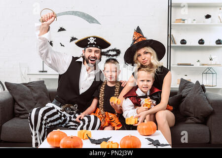 Portrait de famille dans divers costumes de Halloween à table de café avec des citrouilles à la maison Banque D'Images