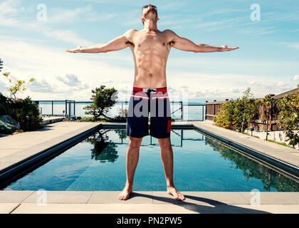 Homme à côté de piscine avec bras levés vers le ciel à la recherche dans la crainte Banque D'Images