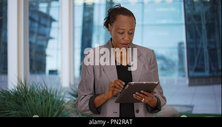 Older black woman utilise digital tablet outside office building Banque D'Images