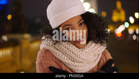 Black woman wearing sweater essayant de garder au chaud en vacances à Paris la nuit Banque D'Images