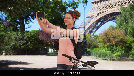 Caucasian brunette sur vélo à Paris s'arrête pour prendre près de Eiffel Tower selfies Banque D'Images