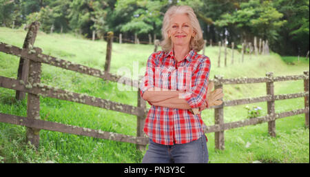 Smiling mature woman farmer posing avec confiance sur l'extérieur de la propriété de campagne Banque D'Images