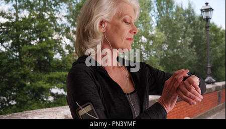 Senior woman mettant en oreillettes et vérification de suivi d'entraînement avant de remise en forme Banque D'Images