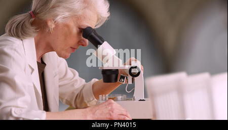 Mature femme scientifique ou chercheur en médecine à l'échantillon au microscope en Banque D'Images