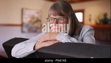 Pensive senior lady tête reposant sur les mains et la pensée à elle-même dans la salle de séjour Banque D'Images