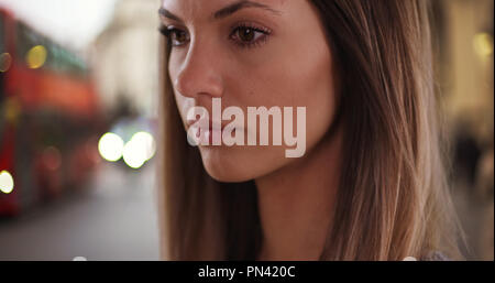 Close-up of millennial fille dans son 20s looking pensive en extérieur dans London street Banque D'Images