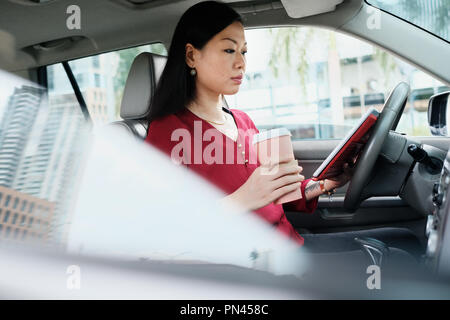 Chinois occupé Business Woman Working in Car With Tablet Banque D'Images