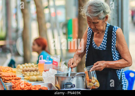 Bangkok, Thaïlande - 23 avril 2017 vieille femme non identifiée : vendeur de rue est la vente de boulettes de viande frite à son client. Banque D'Images