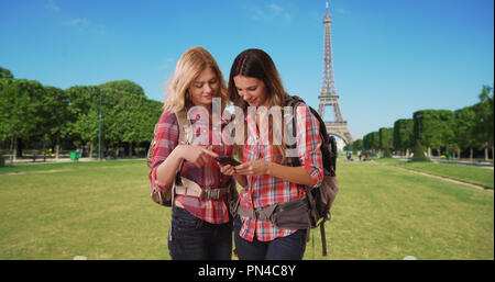 Paire de femme blanche backpackers contrôle site sur smartphone près de Eiffel Tower Banque D'Images