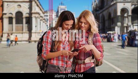 Couple de femmes backpackers à Venise contrôle de téléphone dans la place St Marc Banque D'Images