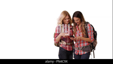 Deux femmes backpackers using cell phone on white background with copy space Banque D'Images