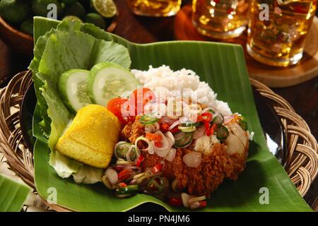 Geprek Sambal Matah Ayam. L'alimentation de rue Fusion plat de poulet frit du sud surmontée de Sambal Matah, les Balinais - Chili salsa à la citronnelle. Banque D'Images