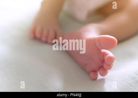 Peu de petits pieds et les orteils de l'heureux nouveau-né de dormir dans le lit bébé dans la lumière du soleil du matin, la famille et le bébé en santé concept. focus sélectif et Banque D'Images