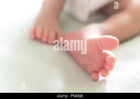 Peu de petits pieds et les orteils de l'heureux nouveau-né de dormir dans le lit bébé dans la lumière du soleil du matin, la famille et le bébé en santé concept. focus sélectif et Banque D'Images