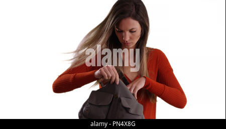 Jeune femme à la recherche grâce à une bourse sur fond blanc solide Banque D'Images