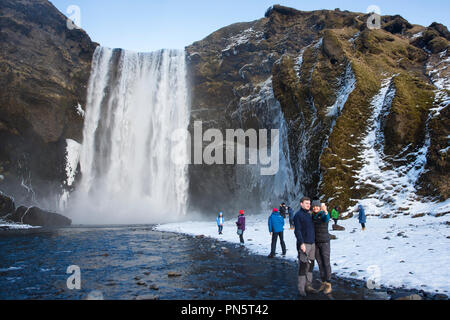 Les touristes à Skogar spectaculaire waterfall - Skogar - dans le sud de l'Islande avec les eaux de fusion glaciaire jaillissant Banque D'Images