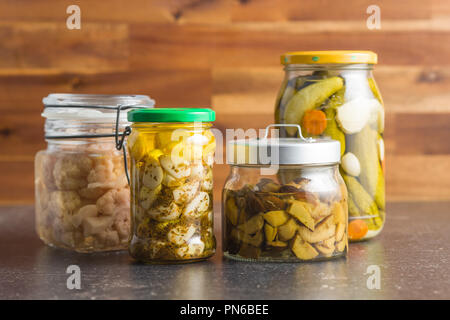 Légumes marinés dans le bocal. Les champignons, choux-fleurs, concombres et l'ail sur la table de cuisine. Banque D'Images