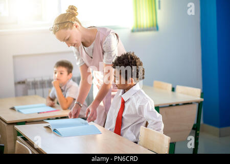 Aider les enfants d'enseignants avec leurs devoirs en classe à l'école Banque D'Images