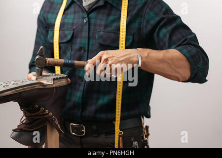 Portrait d'un cordonnier mesurant une chaussure avec ruban de mesure en atelier Banque D'Images