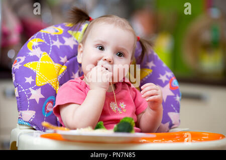 Baby toddler eating in chair Banque D'Images