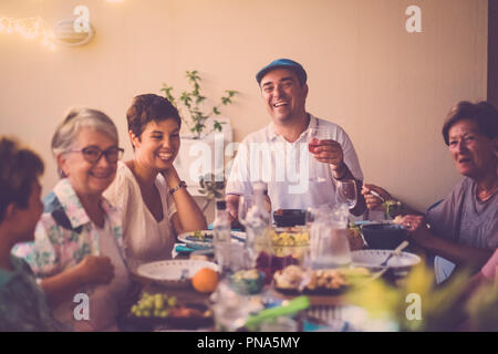 Happy group d'âges différents gens célébrer et s'amuser ensemble dans l'amitié à la maison ou au restaurant. Acclamations et grillage avec cocktails et Banque D'Images