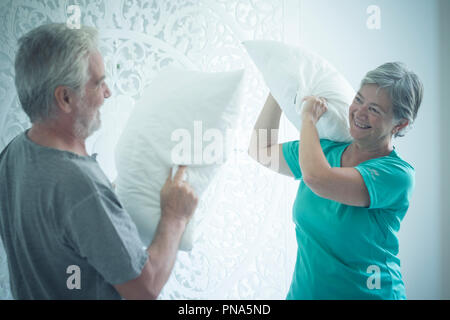 D'âge mûr à la maison à jouer à la guerre avec les coussins sur le lit. matin activité pour l'homme et la femme d'avoir du plaisir. La bonne humeur et la vie foreverness co Banque D'Images
