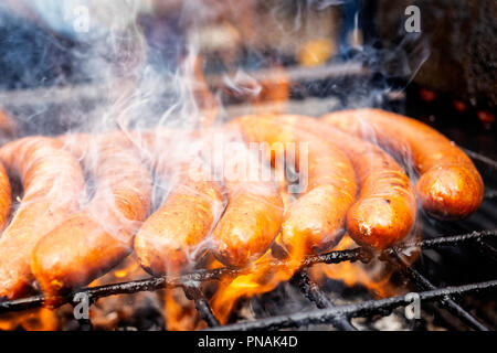 Saucisses européennes sur le gril. Des flammes et de la fumée. Banque D'Images