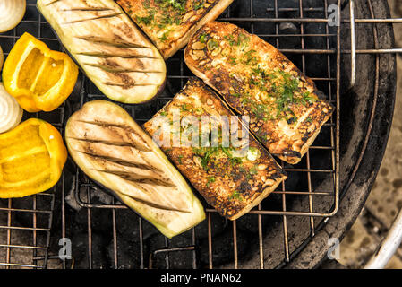 Close up of pain à l'ail chaud et assortiment d'aubergines grillées, oignons et poivrons sur la grille en métal de grand ronde grill extérieur. Focus sélectif. Banque D'Images