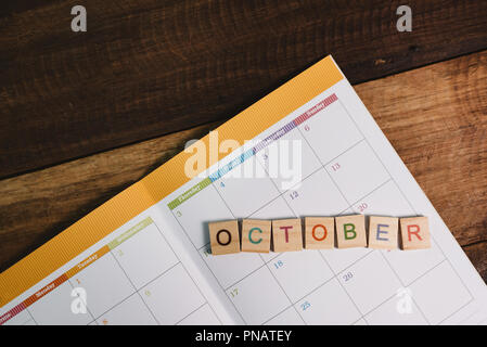 Gros plan du planificateur sur tuile alphabet octobre calendrier livre sur table en bois . Et de planification octobre mois concept Banque D'Images