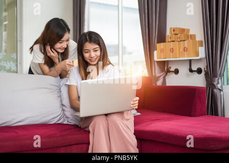 Deux jeunes fille asiatique indépendant privé d'affaires travaillant à domicile bureau avec ordinateur portable assis sur un canapé. Emballage livraison Magasinage en ligne Banque D'Images